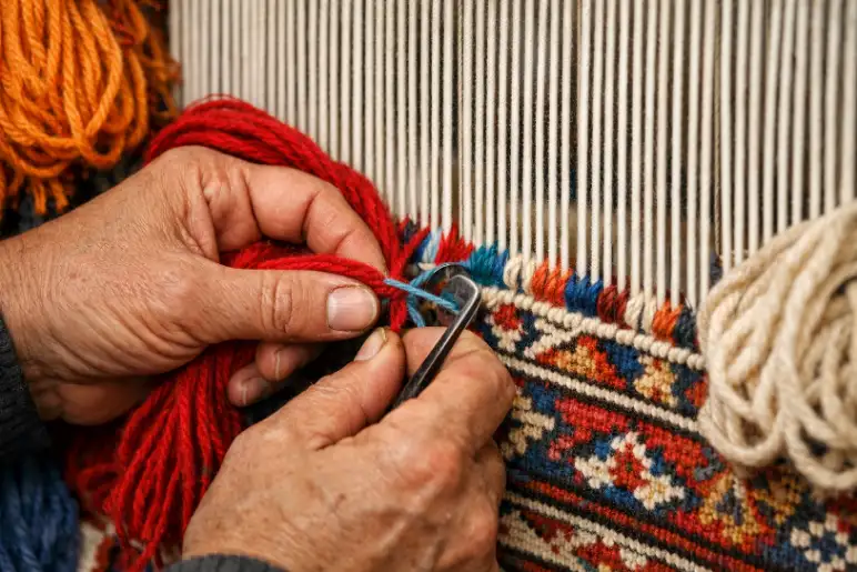 Indian artisans hand-knotting rug on loom showing traditional craftsmanship and detailed weaving process – Hasida Rugs Collection